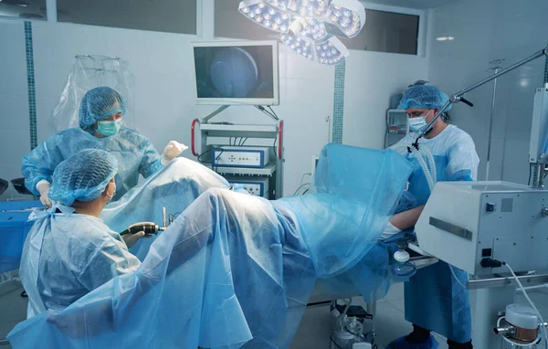 Team of surgeons viewing inside patient body with laparoscopic camera — Stock Photo, Image