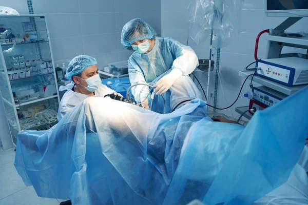 Perawat membantu ahli bedah dengan kontrol kamera laparoskopik selama operasi — Stok Foto
