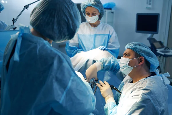 Хирург с медсестрами, выполняющими операцию с лапароскопическим оборудованием — стоковое фото