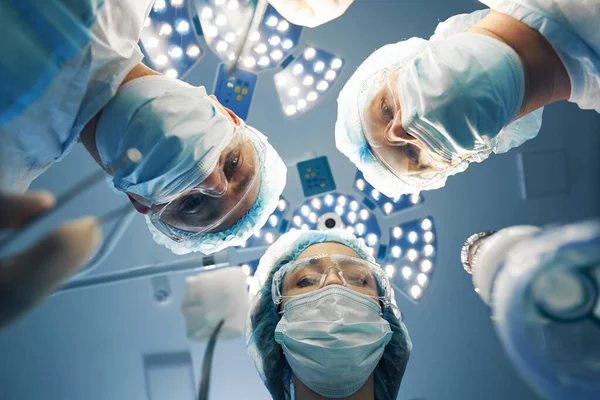 Três médicos se curvando sobre o paciente durante a operação laparoscópica — Fotografia de Stock