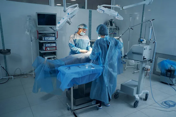 Dos expertos en cirugía que realizan operaciones laparoscópicas al paciente — Foto de Stock