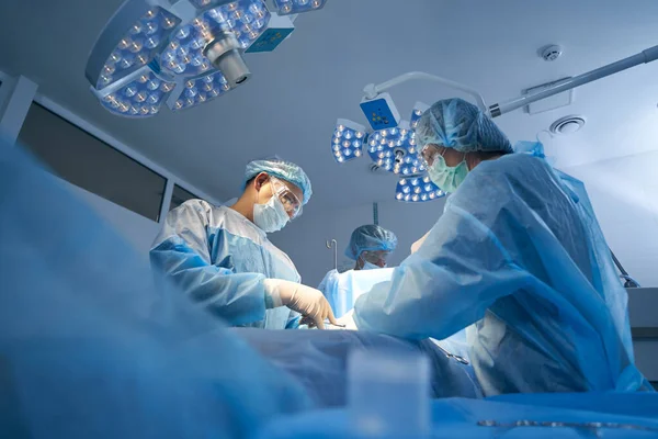 Équipe chirurgicale opérant dans une salle médicale stérile — Photo