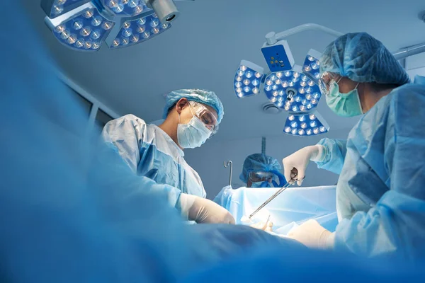 Nurse wiping incision with gauze in forceps during operation — Stock Photo, Image