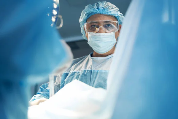 Allvarlig kirurg tittar på kameran under operationen — Stockfoto