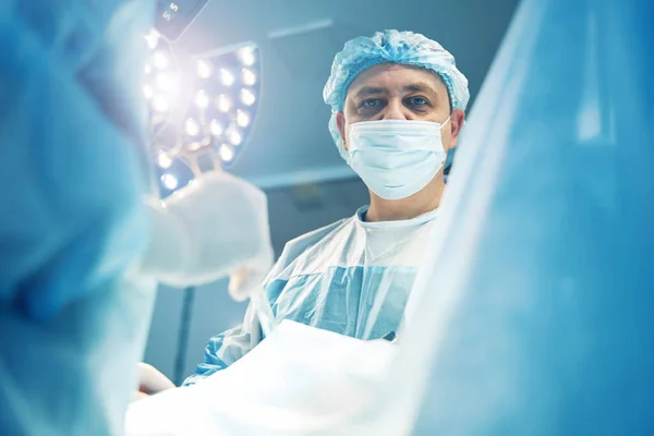 Homem especialista em cirurgia olhando em linha reta durante a operação laparoscópica — Fotografia de Stock