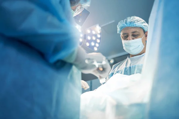 Cirurgião concentrado trabalhando na operação do abdômen na sala de cirurgia — Fotografia de Stock