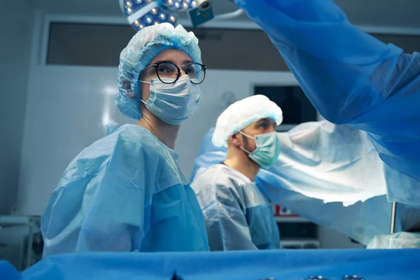 Female doctor in glasses looking aside in operation room — Stock Photo, Image