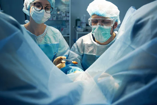 Nurse taking out bloody gauze with forceps during operation — Stock Photo, Image