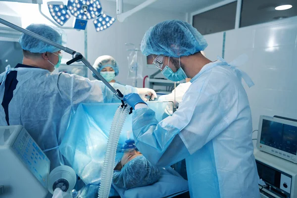 Mannelijke anesthesist die anesthetisch gas levert via masker Stockfoto