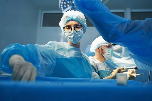 Female surgery assistant taking another instrument from tray — Stock Photo, Image