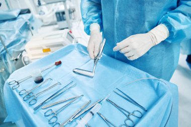 Doktorlar ameliyat için gerekli aletlerle spekulumu masanın üstünde tutuyorlar.