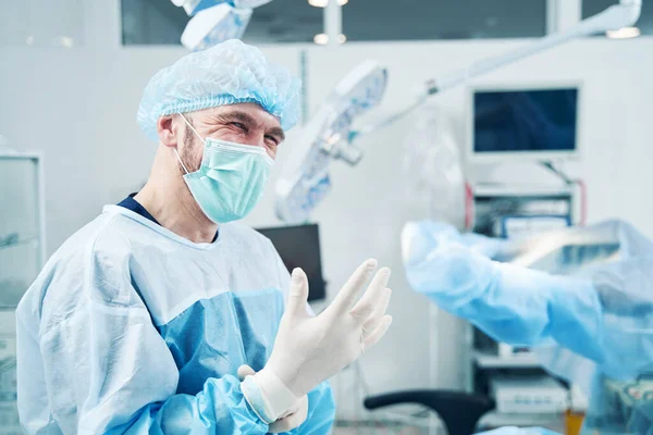 Cerrahi Uzmanı Kameraya Göz Kırparken Elinde Tıbbi Eldiven Tutuyor — Stok fotoğraf