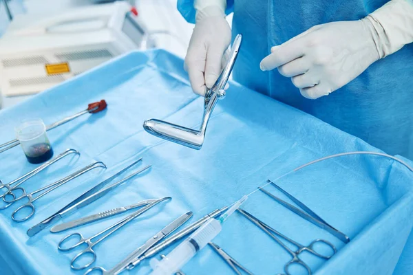 外科用クランプ及びはさみの上にステンレス製の鏡を有する医療用手袋の手 — ストック写真