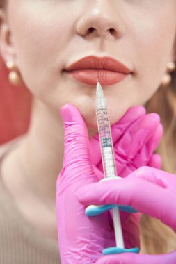Güzel bir bayanın, güzellik salonunda dudak şeklini yükseltmek için iğne olurken kafasının ön kısmından çekilmiş portresi.