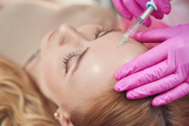 Kafkasyalı zarif bir kadının kozmetoloji merkezinde alnına enjeksiyon yaptırdığı en iyi manzara.