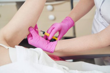 Pembe eldivenli doktor ellerinin kesilmiş portresi güzellik merkezindeki ele deri altı yağ enjekte etmektir.