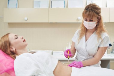 Kafkas dermatoloğunun belden yukarı portresi estetik klinikte zararsız yağ azaltma prosedürü uyguluyor.