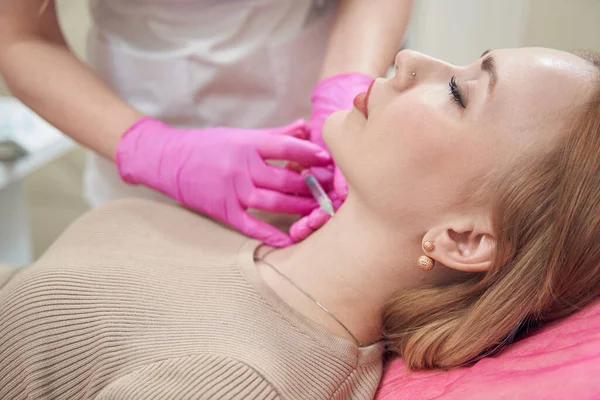 Güzel, zarif bir kadının kozmetik sandalyeye uzanmış portresini yakından çek ve güzellik salonundaki boynuna güzellik prosedürü uygula.