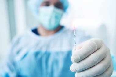 Lateks eldivenli bir tıp çalışanı. Endovenöz terapi için lazer elyafı tutuyor.