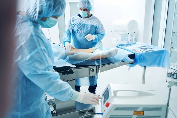 Meslektaşı Monitörü Kontrol Ederken Flübolog Hastanın Bacaklarının Yanında Lazer Lifiyle — Stok fotoğraf