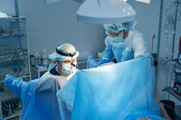 Yoğunlaşmış Doktor Ameliyat Perdesinin Arkasında Hastaya Yardım Eden Bir Hemşireyle — Stok fotoğraf
