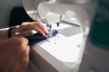 Kırpılmış kafa, profesyonel aletleri kullanırken bir yandan bez tutarken bir yandan da insan ellerine bakıyor.