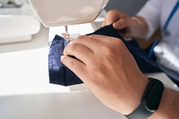 Cropped head close up top view of male hands making clothes with professional tailor device