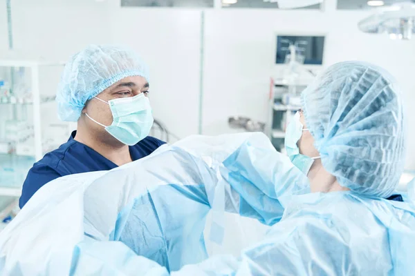 Asistente Reconocido Uniforme Médico Ayudando Cirujano Masculino Usar Bata Con —  Fotos de Stock
