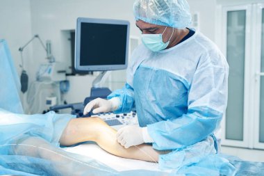 Tıbbi maskeli konsantre bir doktor hastanın derisinin altına dikkatlice bir lazer fiber yerleştiriyor.