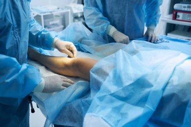 Lateks eldivenli doktor ameliyathanede endovenöz terapi için lazer elyafı kullanıyor.