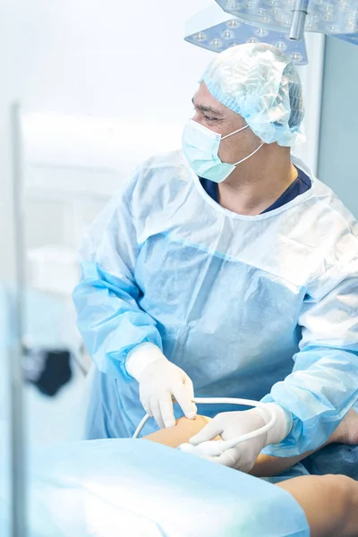 Tıbbi Maske Takan Erkek Doktor Ultrasonla Bacağı Incelerken Video Monitörüne — Stok fotoğraf
