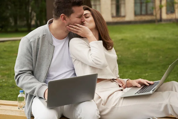 야외에서 노트북을 만들면서 벤치에 남자와 키스하는 좋아하는 — 스톡 사진