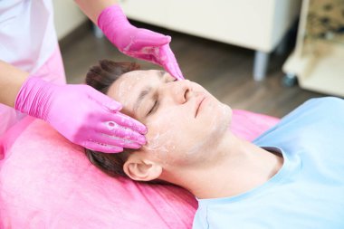 Erkek müşterinin kanepeye uzandığını ve otistik hekimin temizlik yapmadan önce köpükle masaj yaptığını görüyoruz.