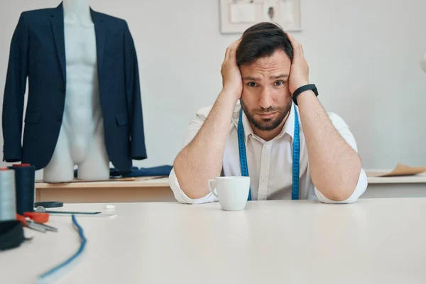 Worried Fashion Designer Puts Head Hands Table Sewing Workshop While — Foto de Stock