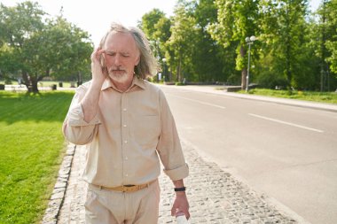 Şakak masajı yaparken gözlerini kapalı tutan ciddi sakallı bir adam.