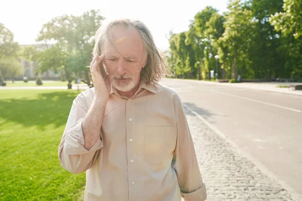Baş ağrısı çekerken şakaklara dokunan olgun bir adam.