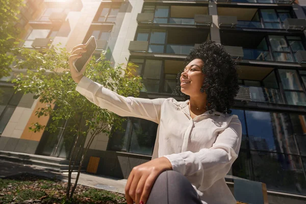 Modern Multiracial Woman Resting Bench Smiling Broadly Takes Selfie Backdrop — ストック写真