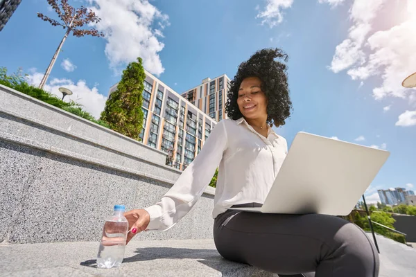 Multiracial Woman Working Laptop Street Her Hand Reaching Bottle Water — Stok fotoğraf