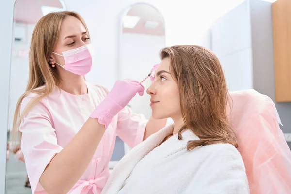 Focused Lady Looking Straight Beauty Parlor While Doctor Doing Cosmetic — Stok fotoğraf