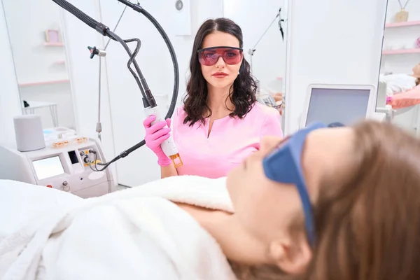 Gözlüklü Kadın Gözlerini Kapatırken Tıbbî Muayenehanede Odaklanmış Bir Doktor Prosedüre — Stok fotoğraf
