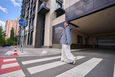 Woman in a hijab and a jacket walks along a pedestrian crossing