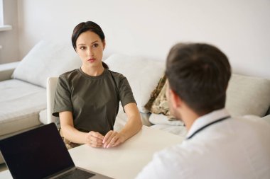 Military woman in a medical facility listens carefully to the doctor professional recommendations and answers his questions