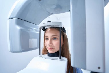 Tranquil adolescent girl undergoing dental radiography procedure on modern equipment in clinic