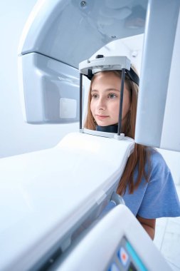 Tranquil adolescent girl undergoing dental radiography procedure on modern equipment in clinic