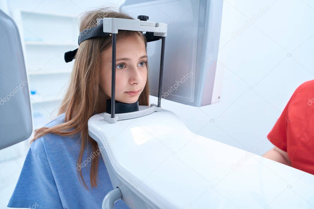 Serene young female patient undergoing digital dental radiography procedure on modern equipment