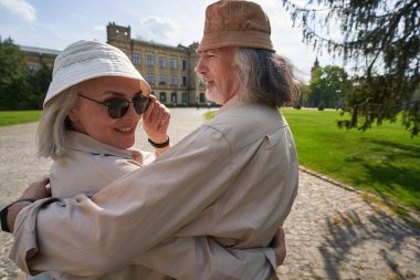 Happy mature man standing close to his wife while being together on walk