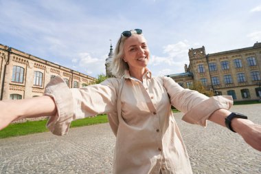 Charming aged woman walking near nice building, posing on camera