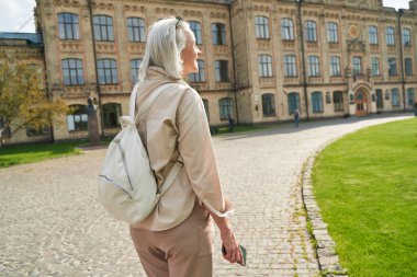 Cute blonde woman expressing positivity while enjoying urban view