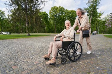 Serious man looking forward while pushing the wheelchair