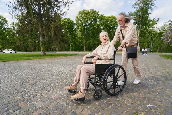 Serious Man Looking Forward While Pushing Wheelchair —  Fotos de Stock